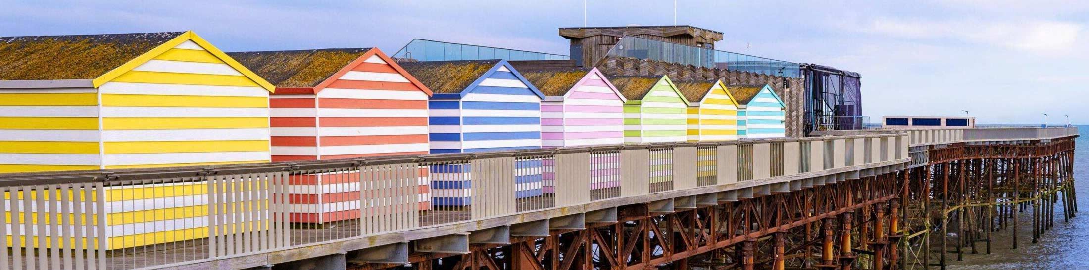 bright coloured beach huts on pier